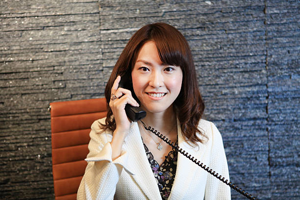 Young Woman receiving calls at reception. dark sparkly granite stone background and warm environment.