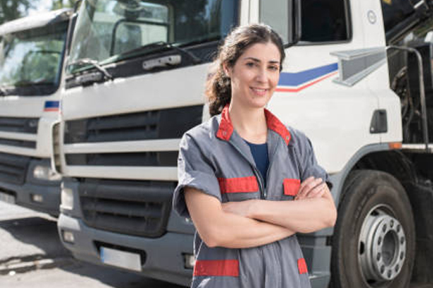 Construction woman worker near to iron structures transportation trucks smiling