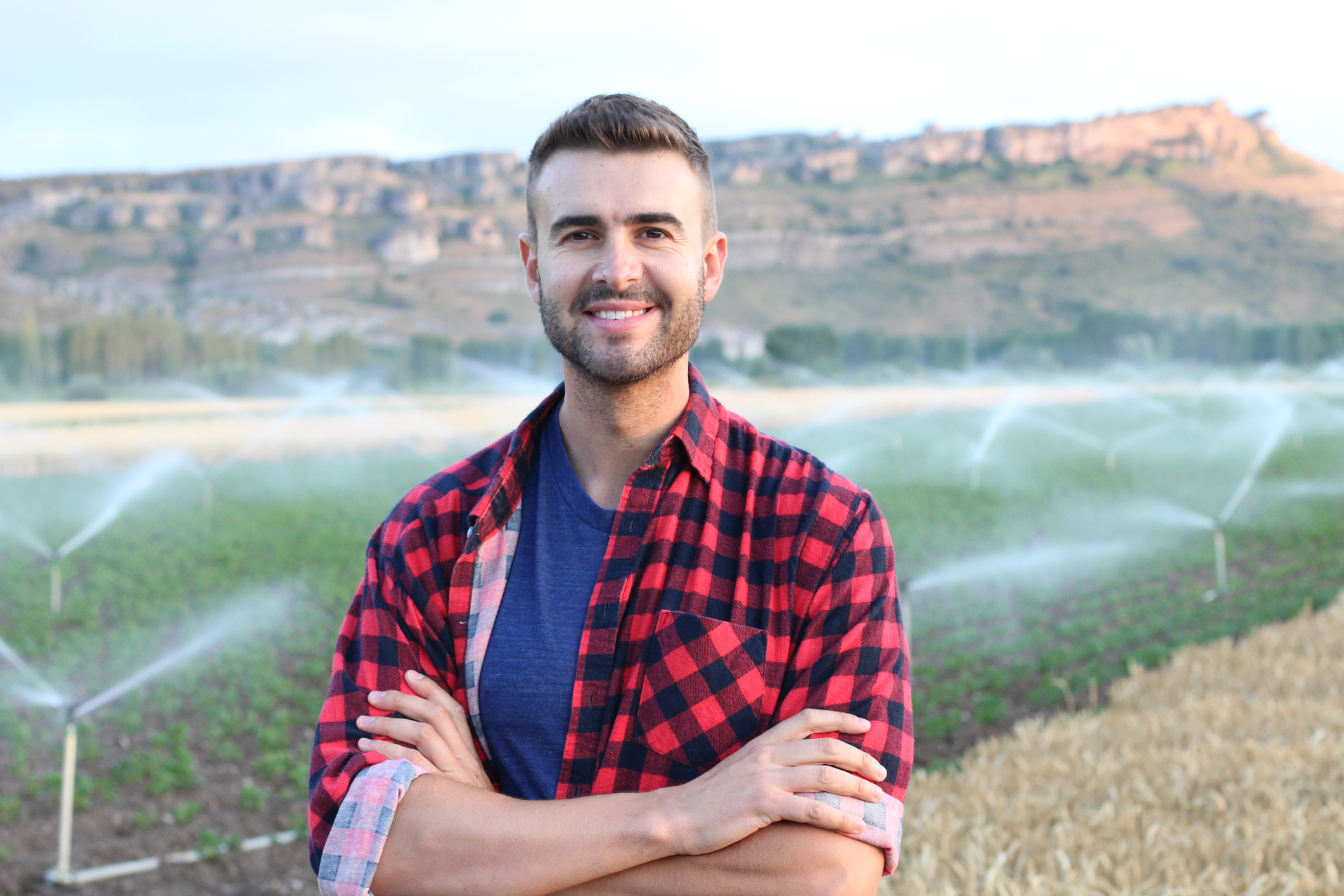 Portrait of young handsome farmer smiling on farmland.