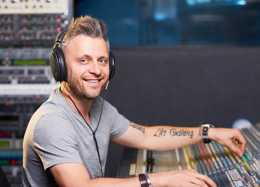 Happy man in earphones mixing sounds in recording studio