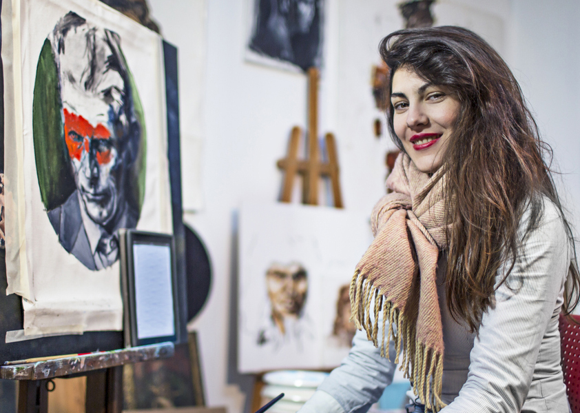 Female artist in her studio surrounded by her painting art