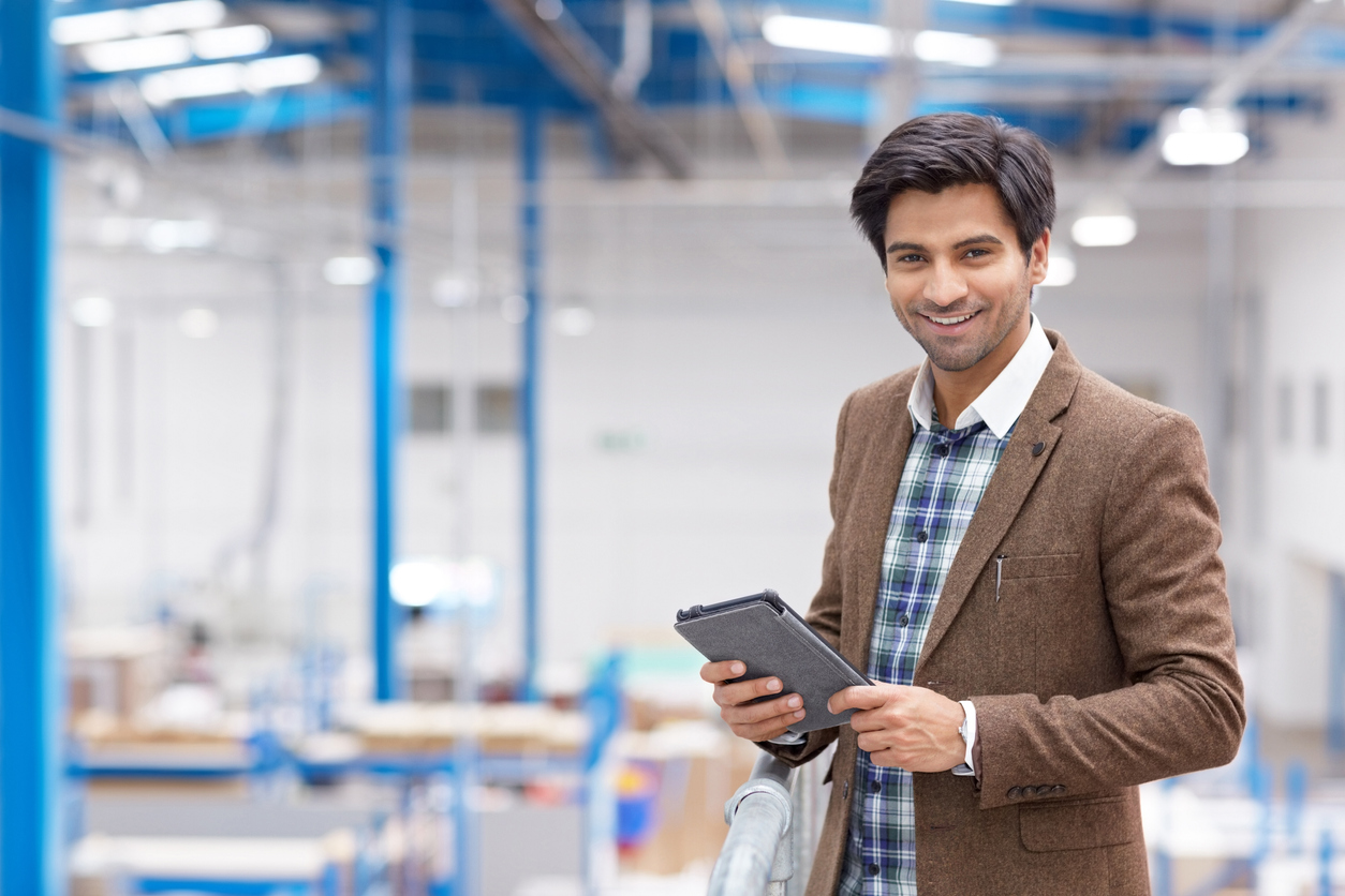 Portrait of happy young businessman with digital tablet in warehouse